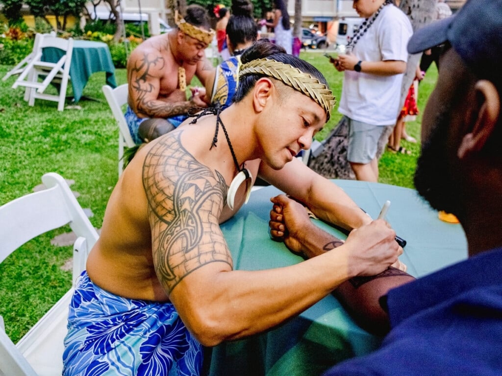 A luau guest getting a temporary Polynesian tribal tattoo at the Waikiki Starlight Luau: Ocean Lawn.