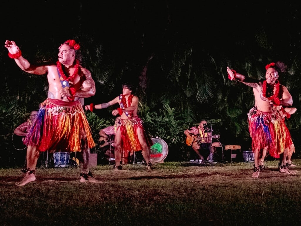 An energetic Samoan dance performance with band and tropical greenery in the background at the Waikiki Starlight Luau: Ocean Lawn.