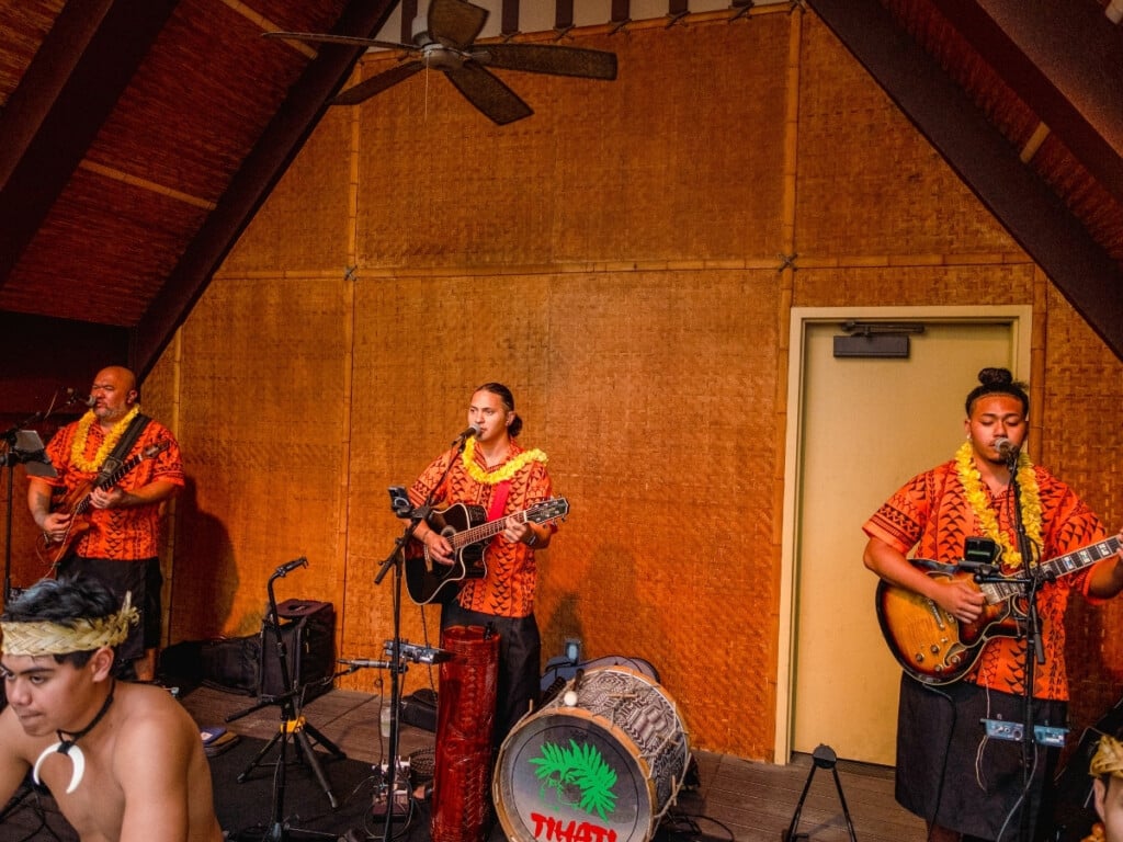 Pre-show performance at Waikiki Starlight Luau: Rooftop featuring a Hawaiian band in colorful aloha shirts and lei playing live music.