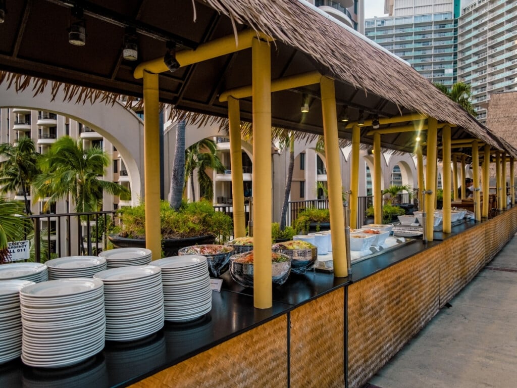 The buffet set-up under tables with thatched roofs at at Waikiki Starlight Luau: Rooftop.