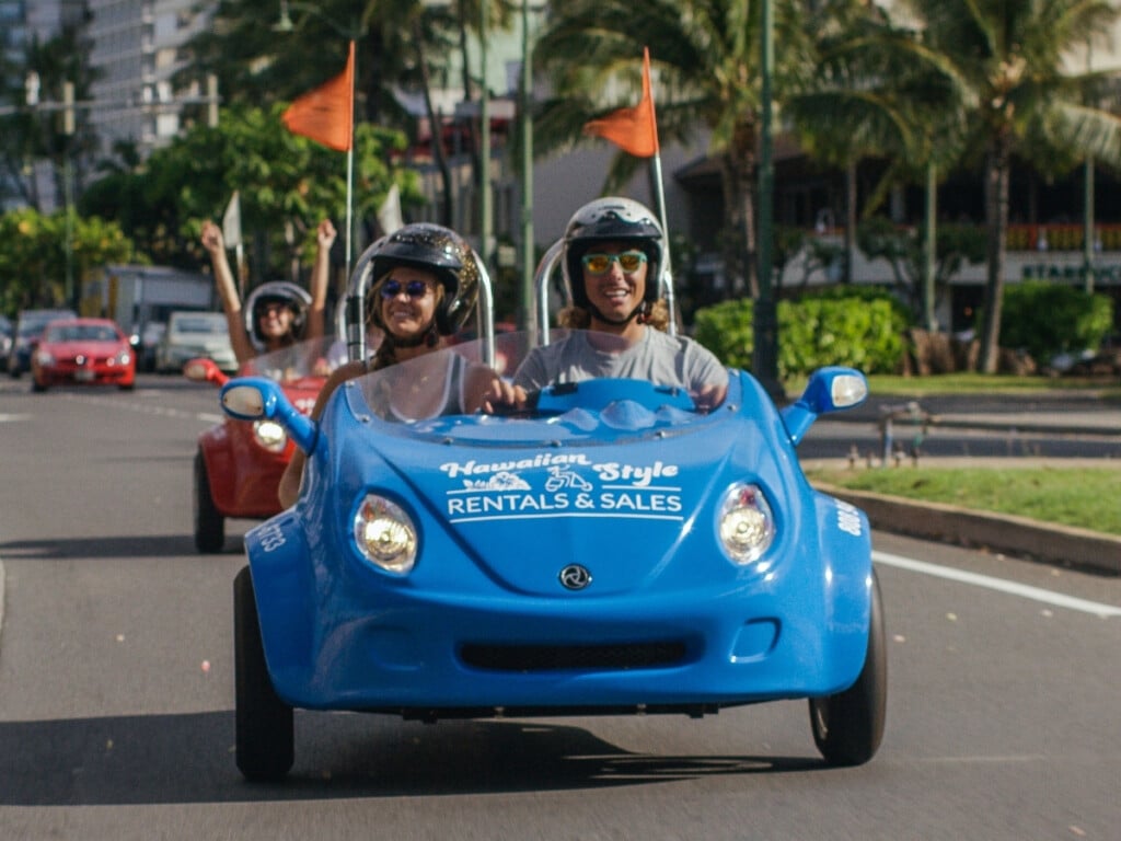 Hawaiian Style Rentals Scoot Coupe cruising down Kalākaua Avenue in Waikīkī.
