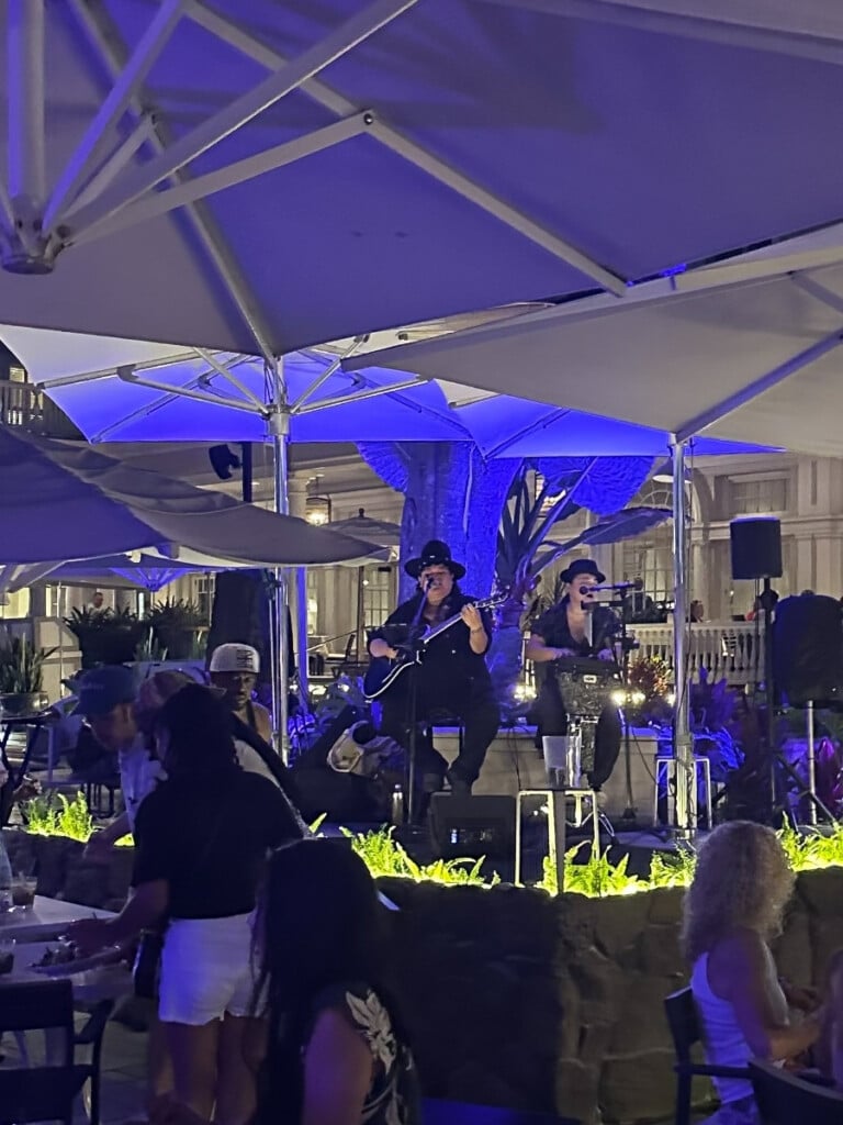 Live music being performed at The Beach Bar under the banyan tree in purple lighting at Moana Surfrider, A Westin Resort in Waikīkī.