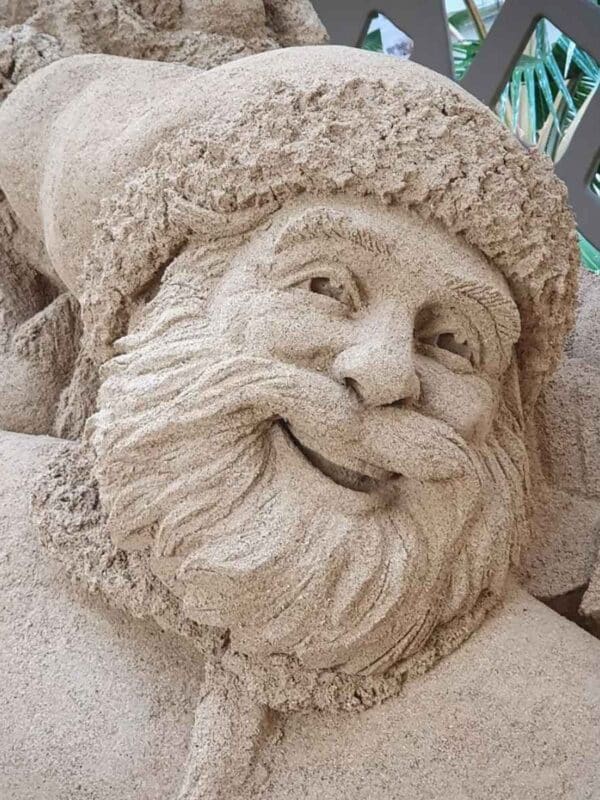Santa Claus sand sculpture with a detailed beard and Santa hat, created for the Christmas season in Waikīkī.