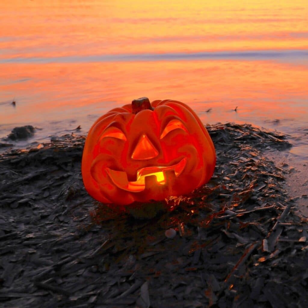 Glowing jack-o’-lantern on the beach at sunset, celebrating Halloween in Hawaiʻi.