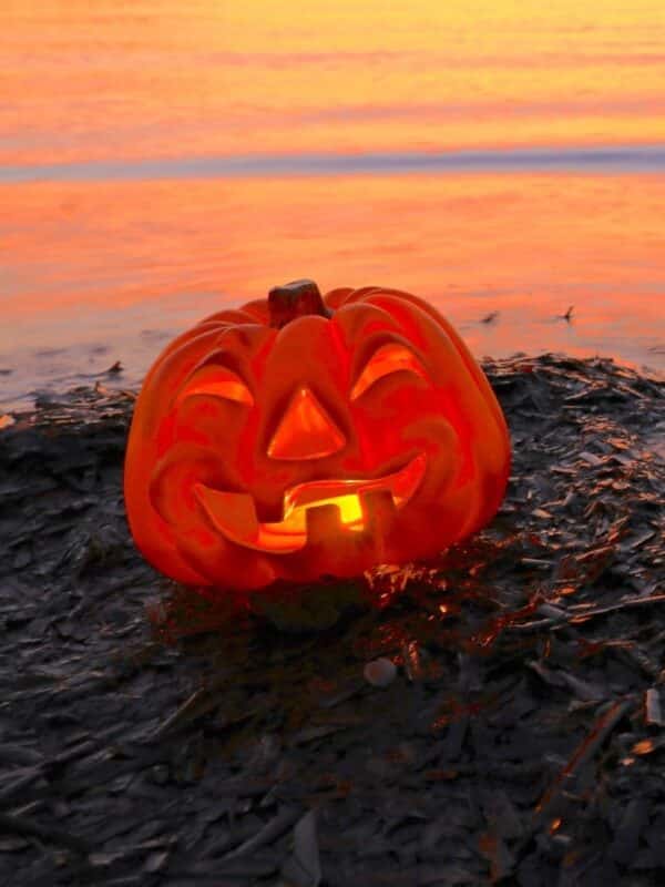 Glowing jack-o’-lantern on the beach at sunset, celebrating Halloween in Hawaiʻi.